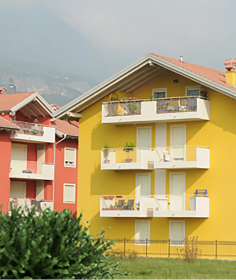 Residenza Alessandra a Rovereto: edificio giallo con balconi bianchi accanto a edificio rosso