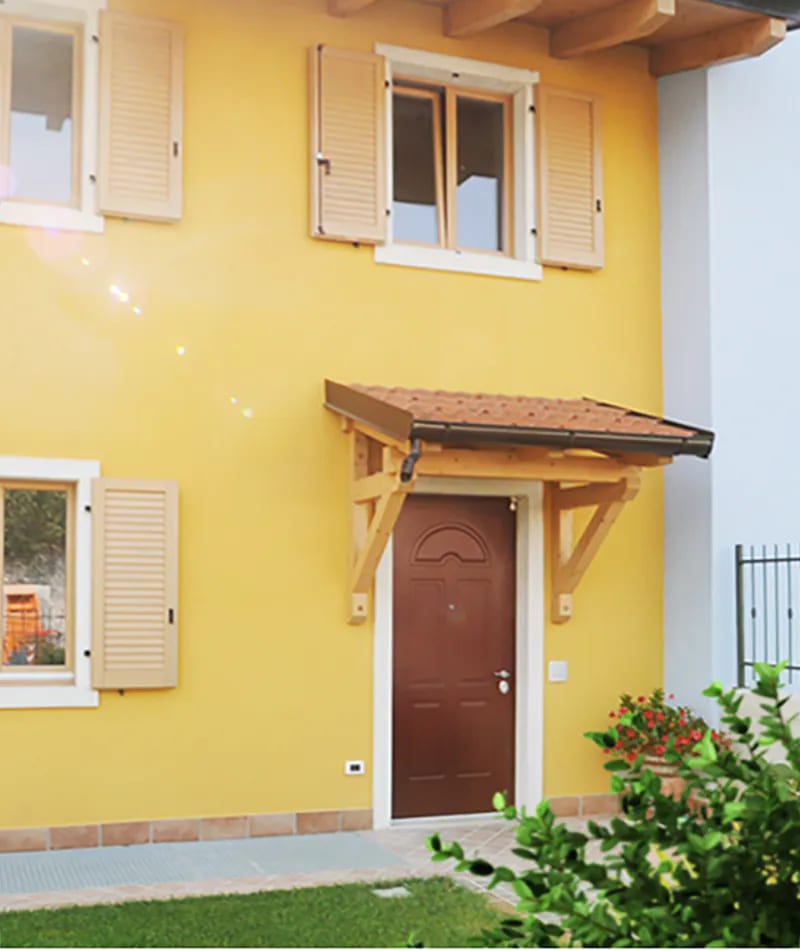 Residenza Amarilli: ingresso con portoncino e tettoia in legno su facciata gialla