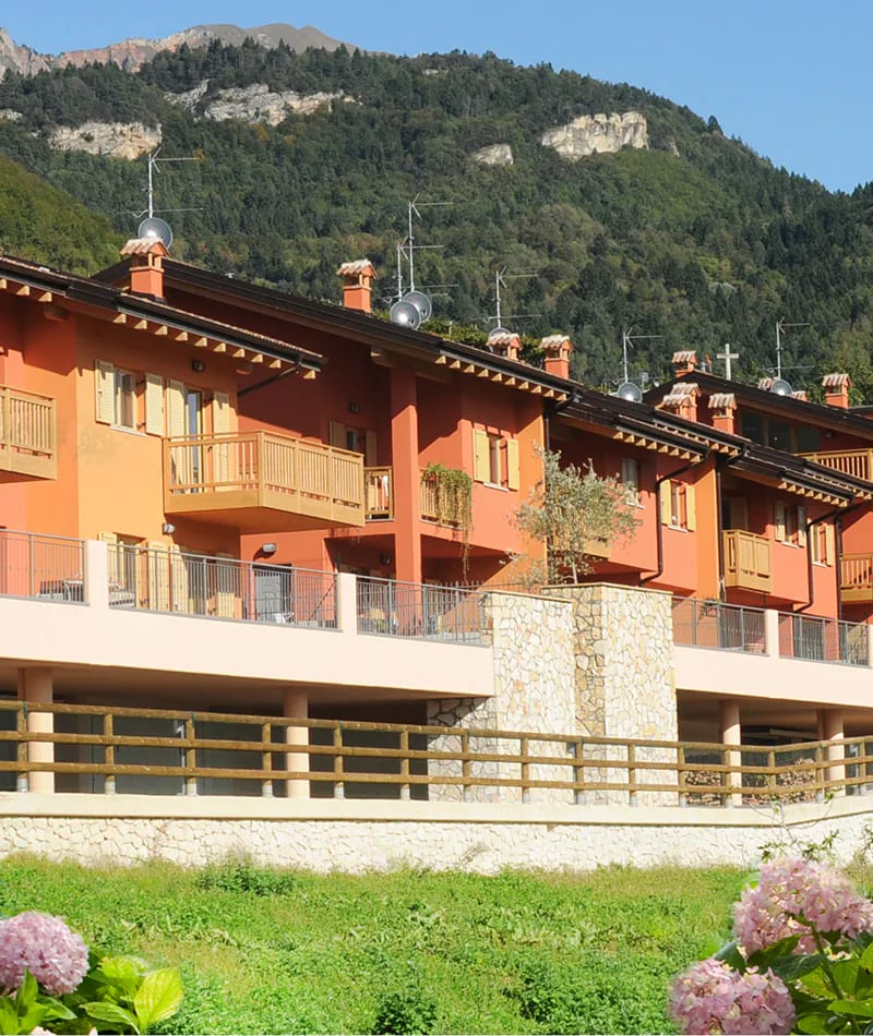 Residenza Francesca a Pedersano: complesso di case a schiera rosse ai piedi della montagna
